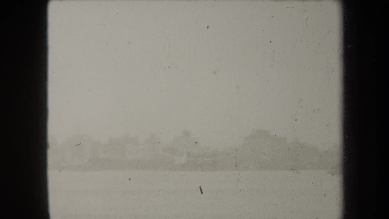 Hazy waterfront view with faint distant buildings across water.