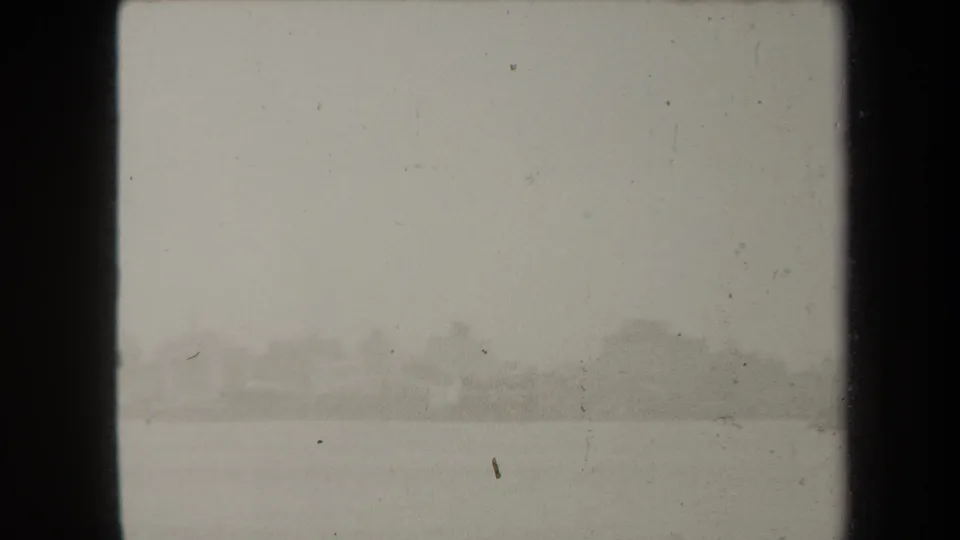 Soft 1938 New York home-movie frame showing water and a faint distant shoreline under overcast light.