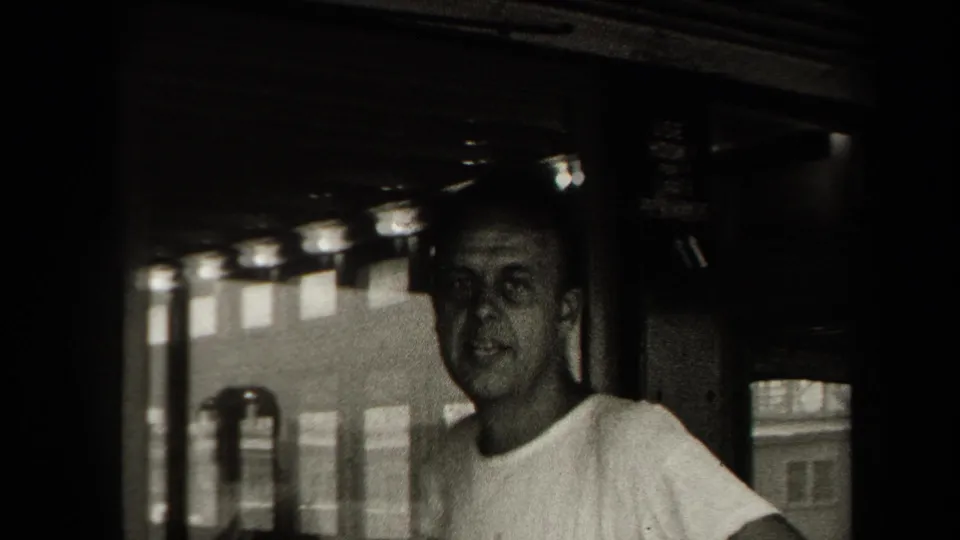 Adult man in a light shirt appears inside an enclosed boat or ferry area in 1938 New York home-movie footage.