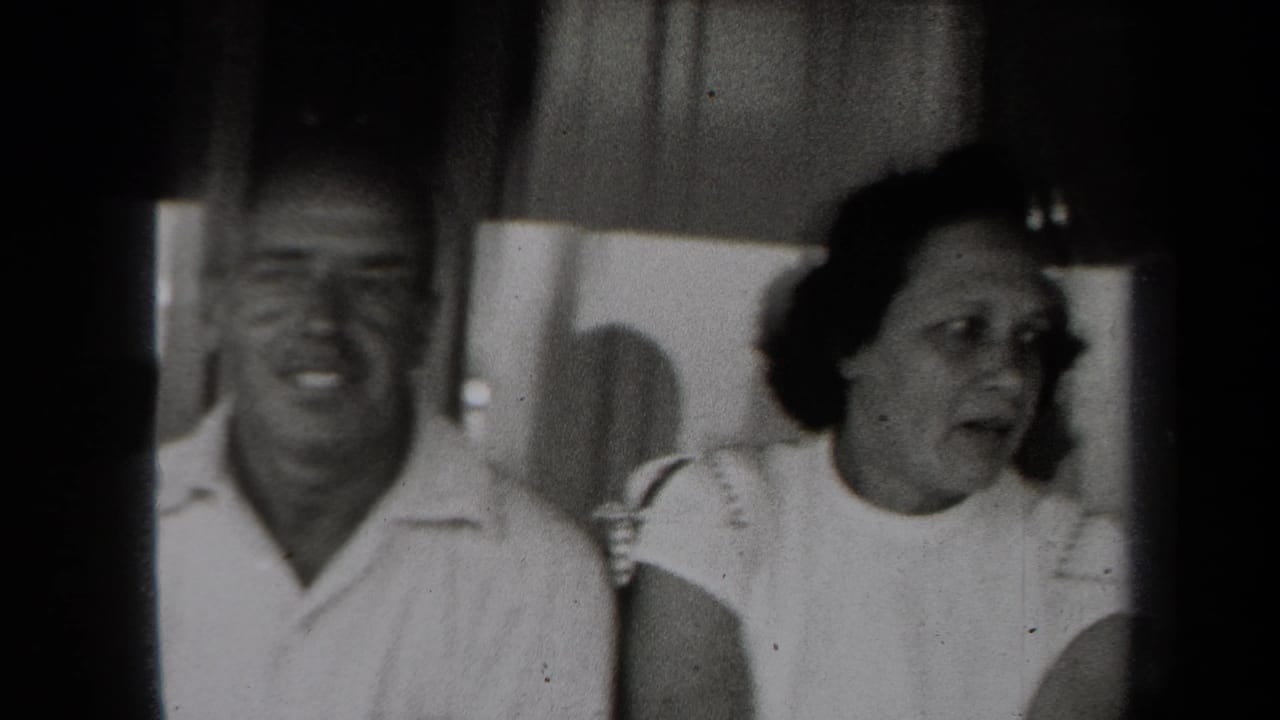 A man and woman appear indoors in a candid 1938 New York 8mm home-movie frame, both seen in soft focus.