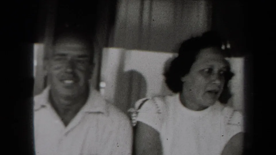 A man and woman appear indoors in a candid 1938 New York 8mm home-movie frame, both seen in soft focus.