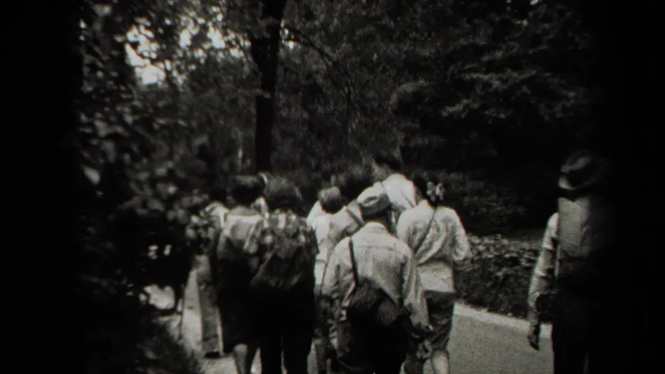 A group of people walks from behind on a tree-lined path in New York, consistent with the supplied 1938 home-movie metadata.
