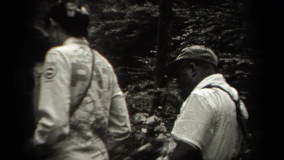1938 New York 8mm frame showing hikers from behind as they move along a shaded forest path.