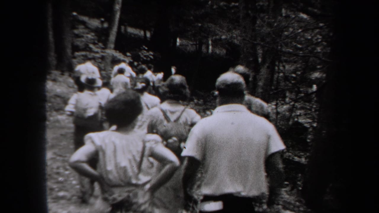 1938 New York home-movie frame showing a small group walking away on a wooded trail in black and white.