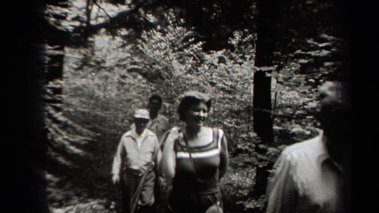 In 1938 New York home-movie footage, several young adults walk along a narrow forest path in sun-dappled light.