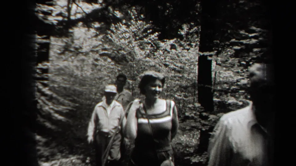In 1938 New York home-movie footage, several young adults walk along a narrow forest path in sun-dappled light.