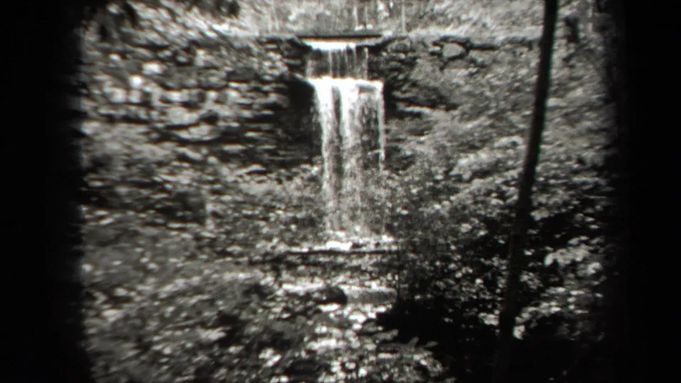 1938 New York black-and-white frame of water falling over a rock ledge into a shallow stream.