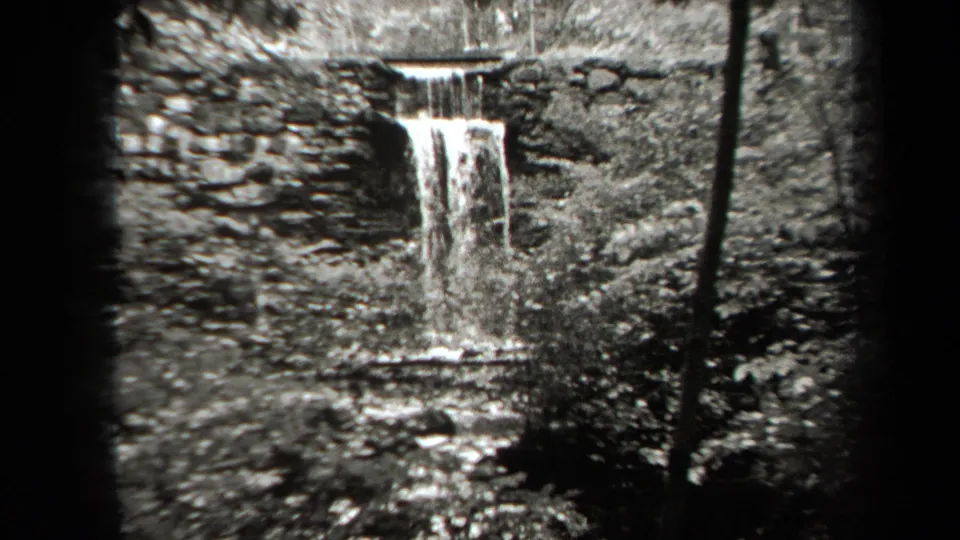 1938 New York 8mm view of a small waterfall, rock face, stream, and surrounding foliage.
