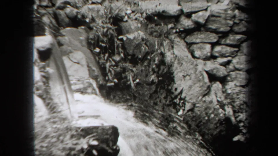 1938 New York frame showing a narrow stream channel bordered by stonework, rocks, and brush.