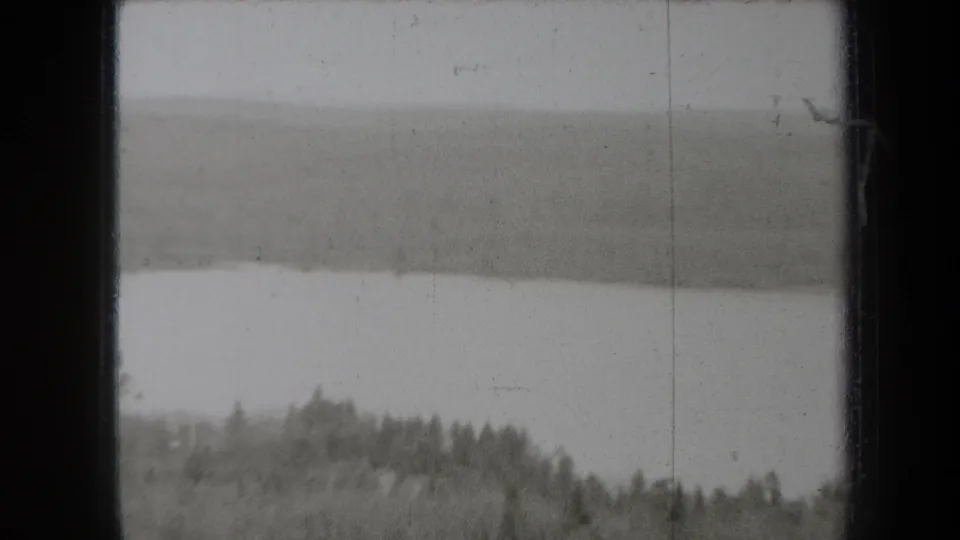 Final 8mm frame showing a soft, hazy distant landscape with treeline and heavy film exposure variation.