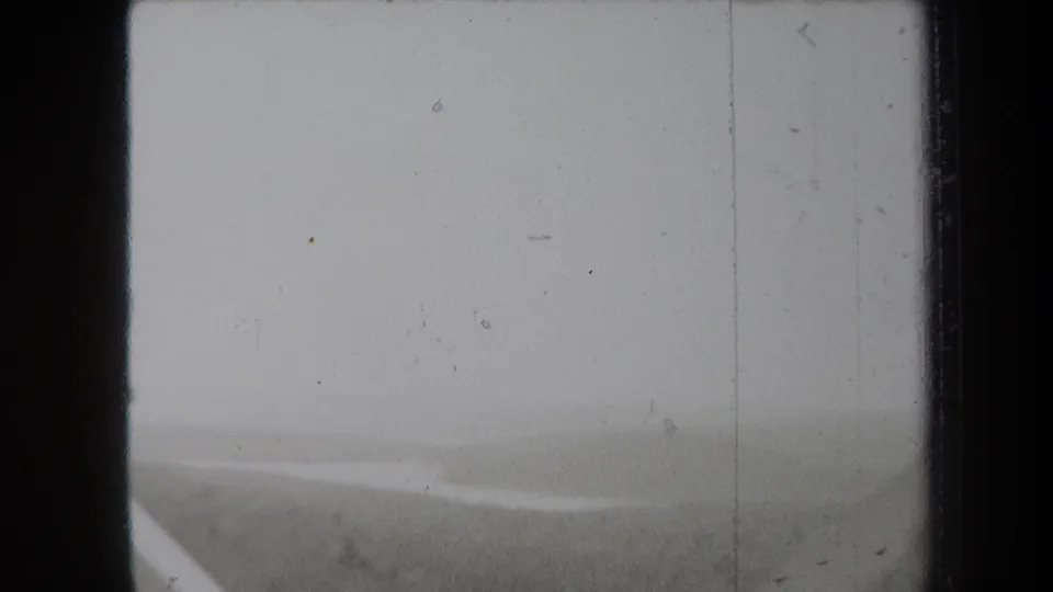 1938 New York 8mm frame showing a hazy landscape through a window-like border, with a faint diagonal road or water edge.