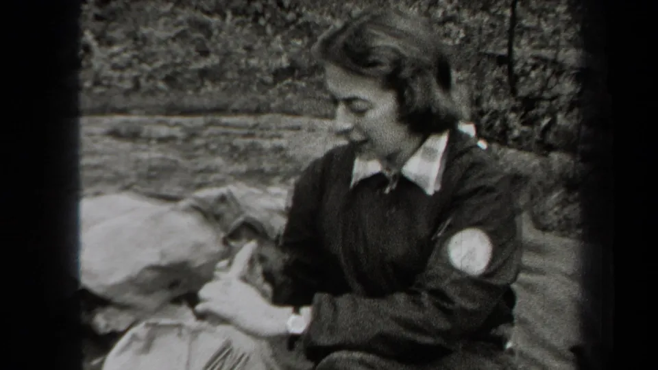 In 1938 New York home-movie footage, a woman sits on a blanket in the woods and appears to prepare food with a fork.