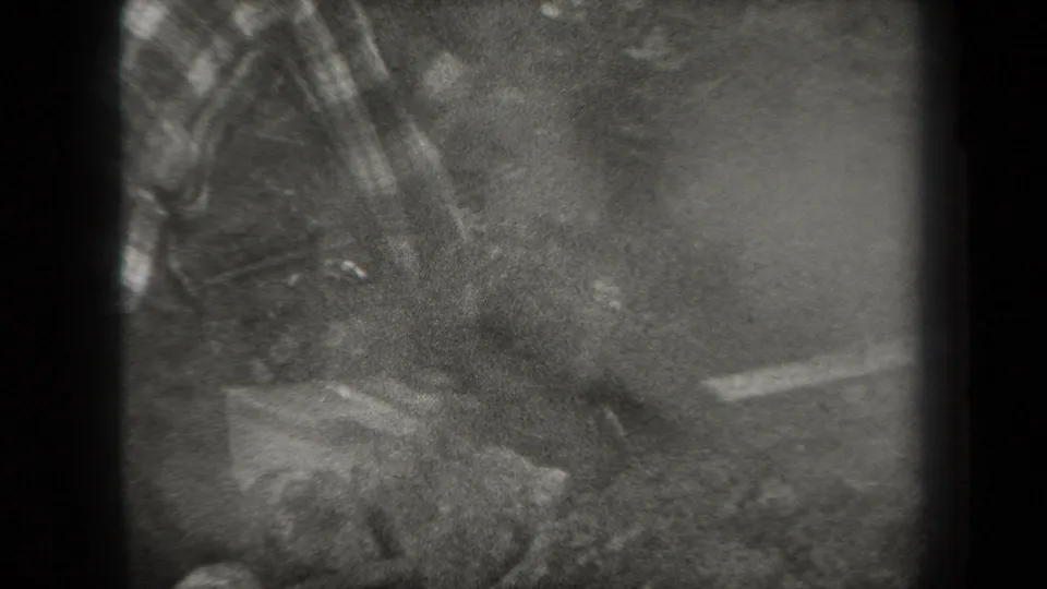 Grainy 1938 New York 8mm frame showing a wooded outdoor area with indistinct activity and heavy vignette at the film edge.