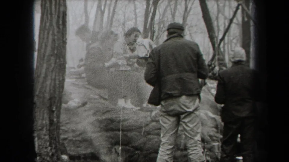 Adults gather around food and smoke in a wooded New York outdoor meal scene recorded on 8mm film in 1938.