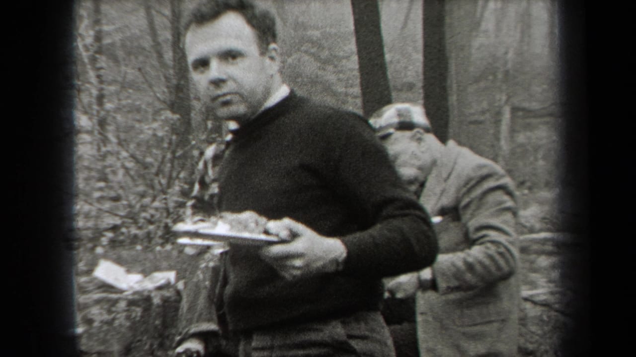 Adult men in a wooded area, one holding a plate while others sit or stand nearby.