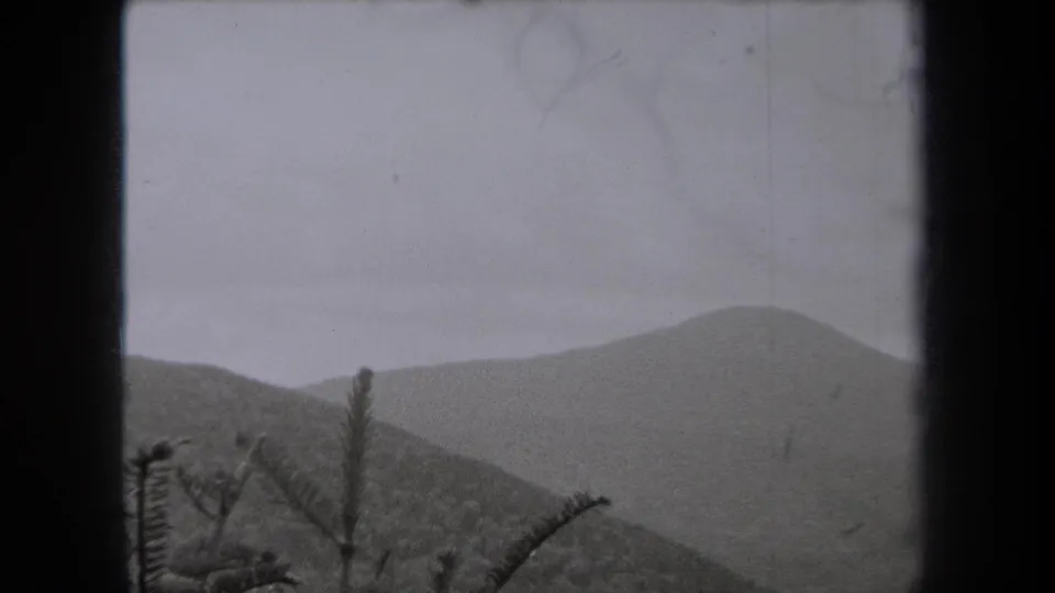 1938 New York home-movie view of a muted mountain ridge, wooded foreground, and pale sky in a grainy 8mm frame.
