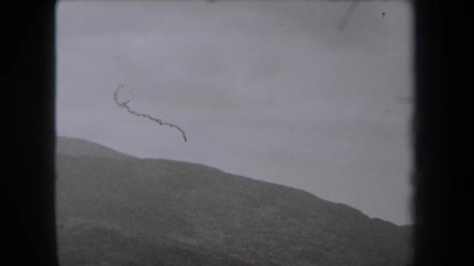 1938 New York landscape frame showing a sloped hillside and cloudy sky, with scratches and grain from the 8mm source.