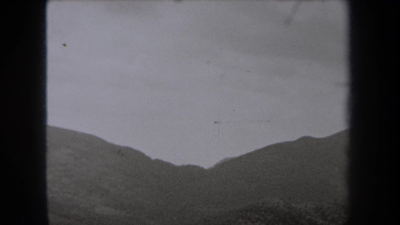 1938 New York 8mm frame showing a distant mountain ridge partly softened by fog under a gray sky.