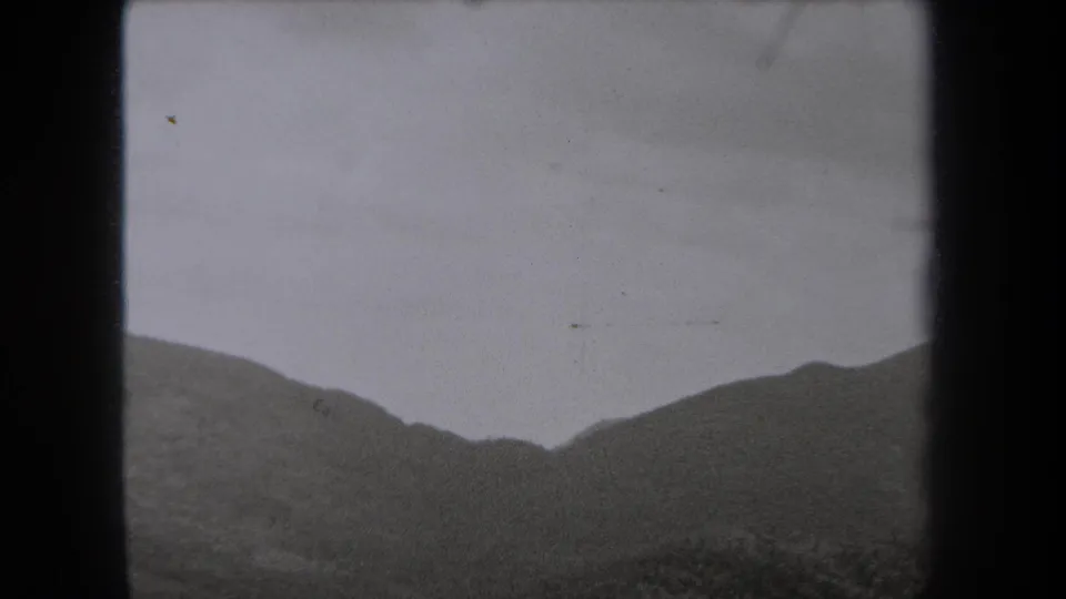 1938 New York 8mm frame showing a distant mountain ridge partly softened by fog under a gray sky.