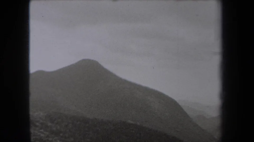1938 New York 8mm frame showing a closer dark slope and a fog-softened valley behind it.