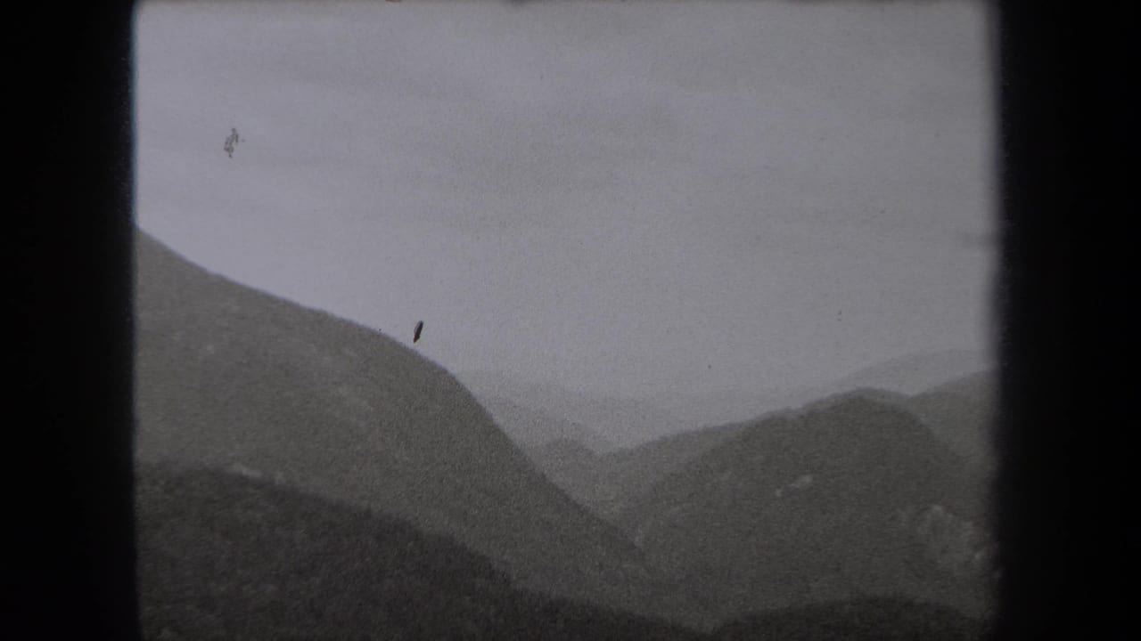 1938 New York 8mm frame showing layered mountain ridges fading into fog beneath an overcast sky.