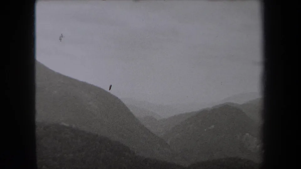 1938 New York 8mm frame showing layered mountain ridges fading into fog beneath an overcast sky.