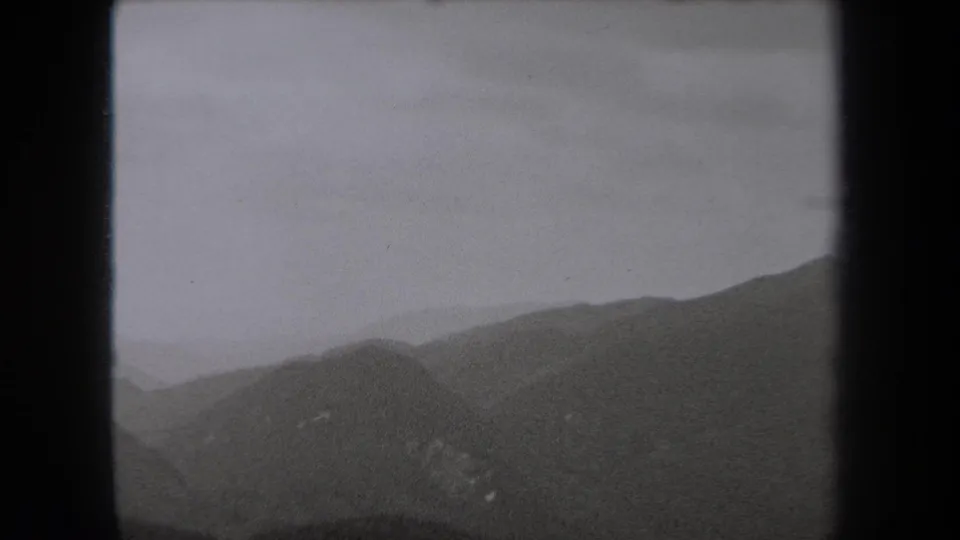 1938 New York home-movie view of dark mountain slopes receding into haze under a pale gray sky.