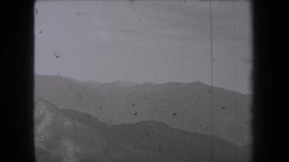 1938 New York 8mm frame looking across multiple low mountain ridges under a pale sky, with grain, dust, and vertical film marks visible.