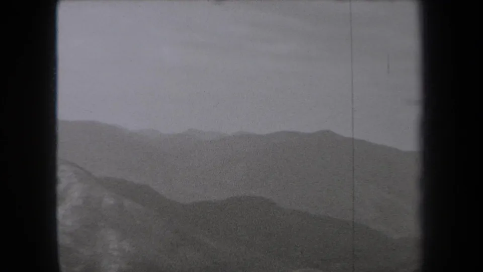 1938 New York 8mm frame showing layered mountain ridges fading into haze beneath a pale sky.