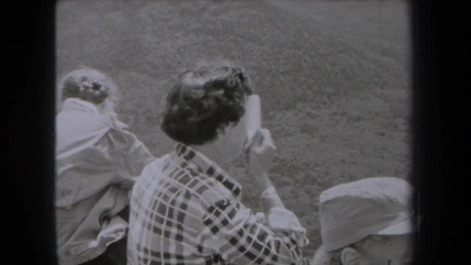 1938 New York home-movie still of a woman combing her hair outdoors, with another seated figure close beside her.