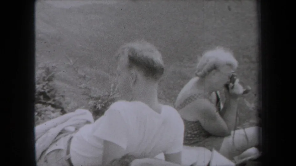 1938 New York outdoor home-movie frame showing a man from behind and a woman photographing from a seated position.