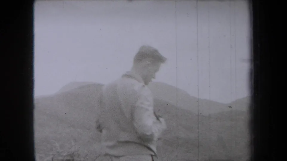 1938 New York home-movie frame showing a man standing on open ground with hills in the background.