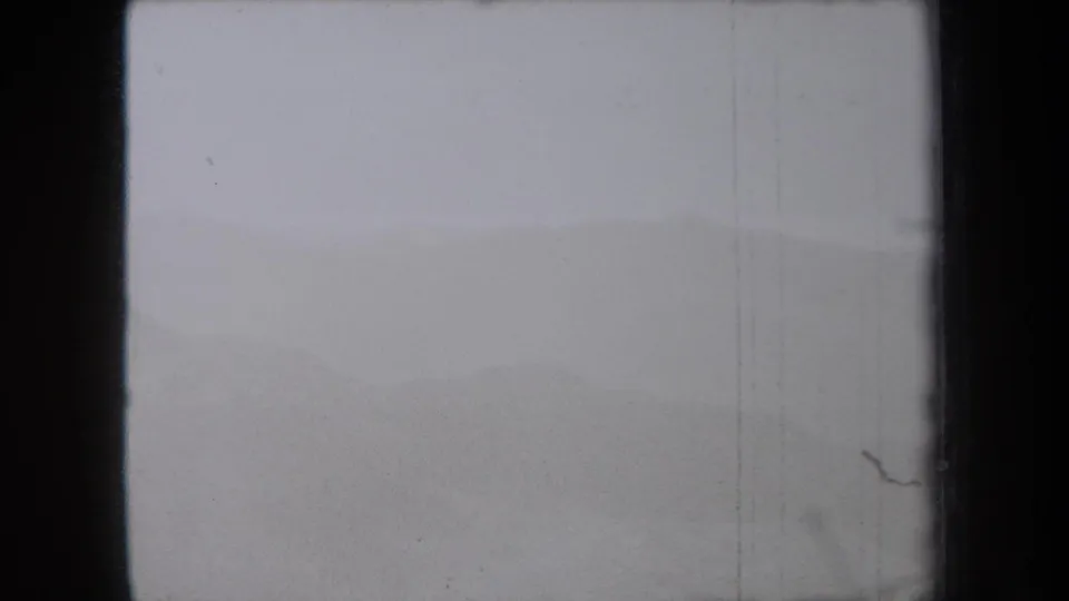 1938 New York home-movie frame showing a washed, hazy dune field with visible film wear and frame-edge darkness.