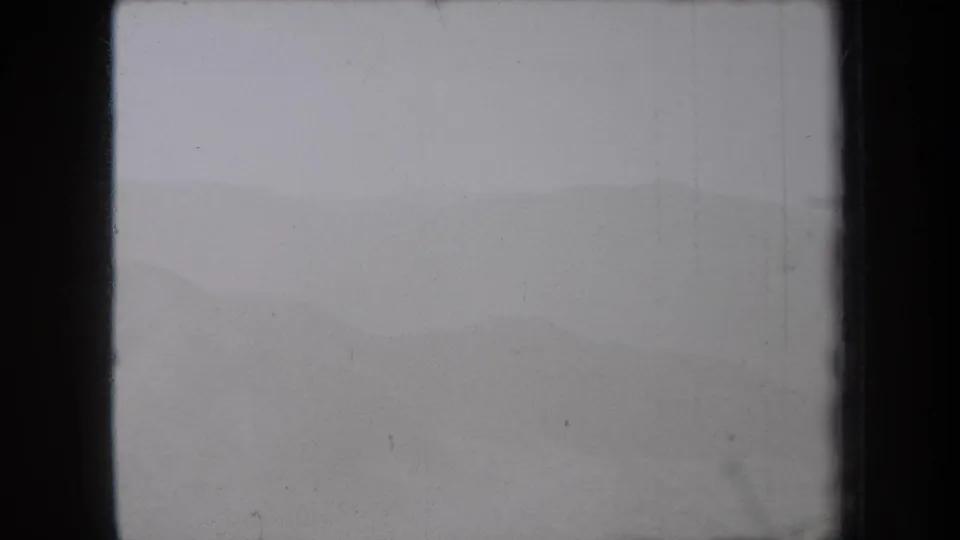 1938 8mm New York footage appears to show a misty mountain slope fading into a gray sky, framed by dark film gate edges.