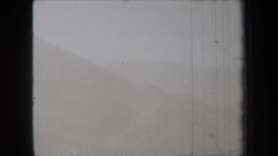 The frame shows hazy New York mountain ridges from a 1938 8mm home movie, with muted contrast and vertical film scratches.
