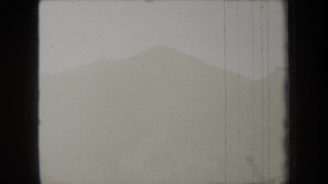 Fog-softened ridge seen through dark 8mm film borders and vertical wear lines.