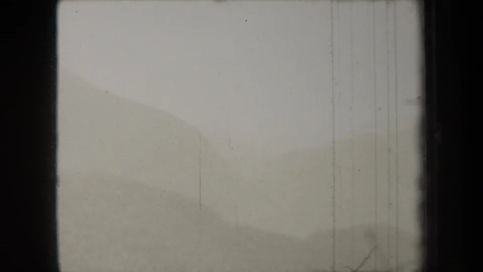 1938 New York 8mm frame with a soft foggy hillside, pale sky, dark film border, vertical wear, and small marks near the edge.