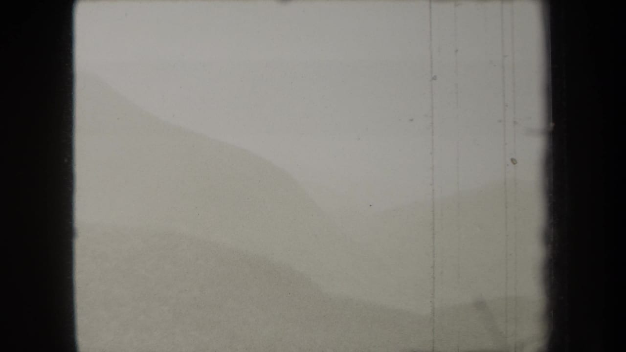1938 New York 8mm frame showing a soft, hazy view of distant hills with film-gate borders and visible vertical wear.