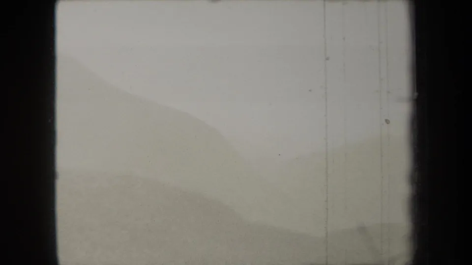 1938 New York 8mm frame showing a soft, hazy view of distant hills with film-gate borders and visible vertical wear.