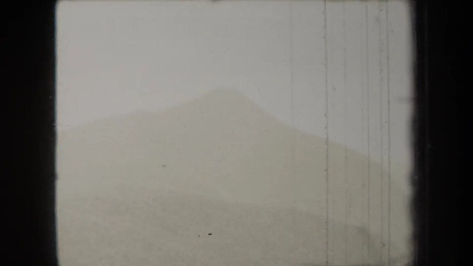 1938 New York 8mm frame with a faint mountain or hill ridge under a pale sky, marked by scratches and film borders.