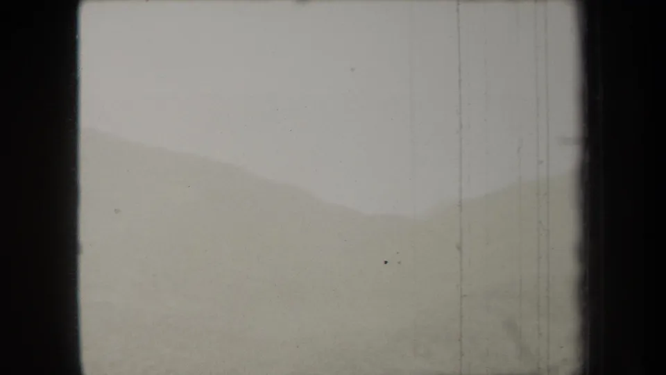 1938 New York 8mm frame showing faint mountain ridges and a washed-out sky with visible scratches and dust.