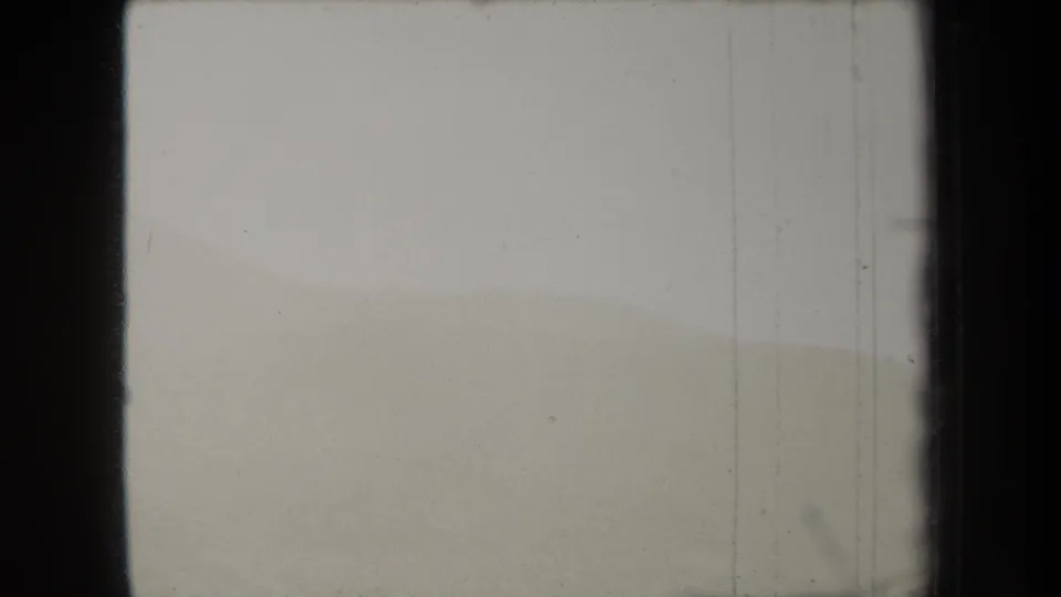 1938 New York 8mm frame showing a very light hillside view with subdued ridges, scratches, dust, and scan borders.