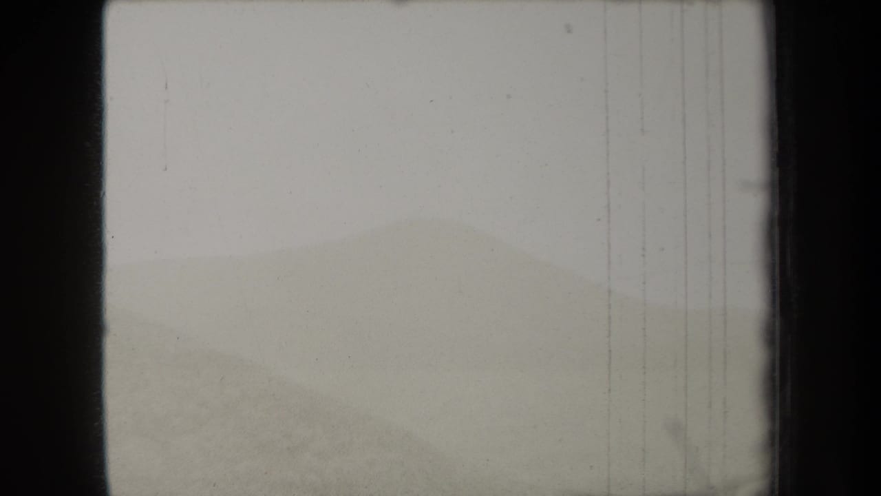 1938 New York 8mm home-movie frame showing pale fog over rolling green hills with visible film grain and border wear.