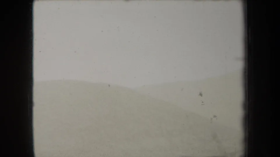 1938 New York 8mm frame of layered hills receding into fog, with dust marks and dark home-movie frame edges.