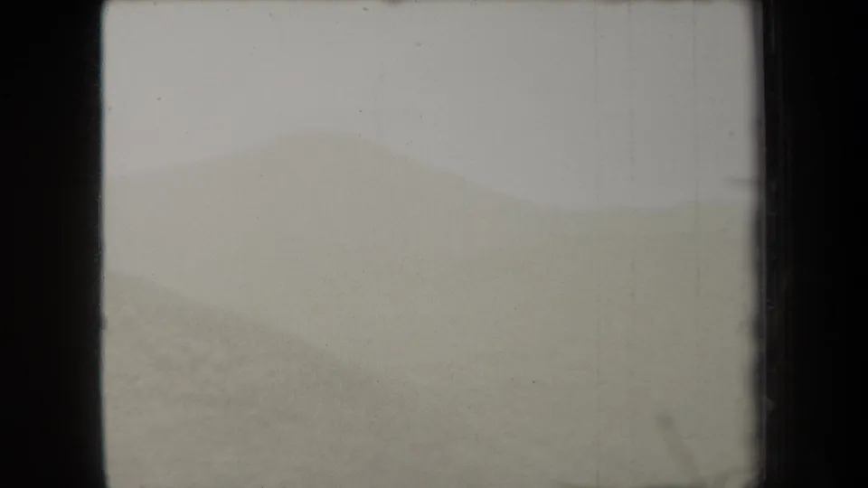 1938 New York 8mm frame showing a fog-muted hillside, soft green terrain, and visible scratches along the film image.