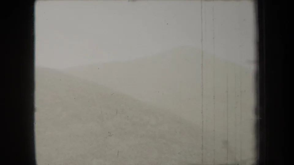 1938 New York 8mm frame showing a soft, hazy dune or low hill under a blank pale sky, with visible film edge and scratches.