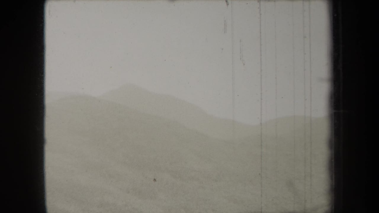 Fog-softened hill ridges under a pale overcast sky with dark film borders.