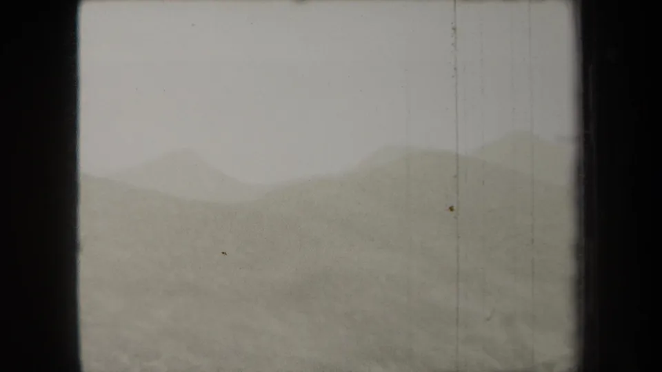 1938 8mm home-movie view of pale sky and low hill forms, with haze reducing detail across the landscape.