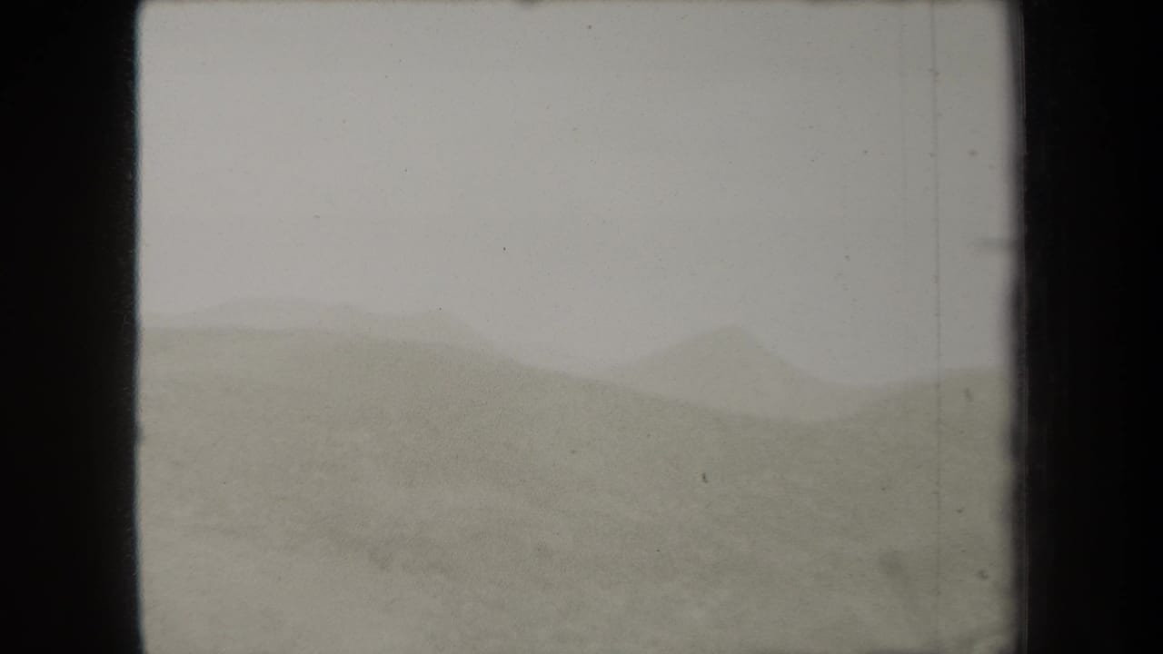 1938 New York 8mm frame showing hazy rolling hills under a grey sky, with soft focus and visible film wear.