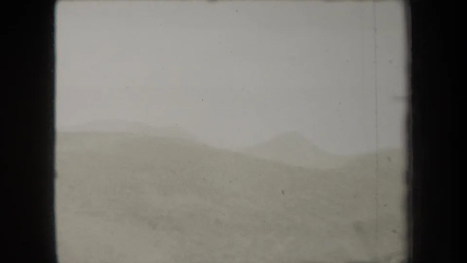 1938 New York 8mm frame showing hazy rolling hills under a grey sky, with soft focus and visible film wear.